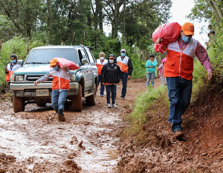 World Vision staff walk along a muddy road in Honduras, delivering comfort kits to a child-friendly space.