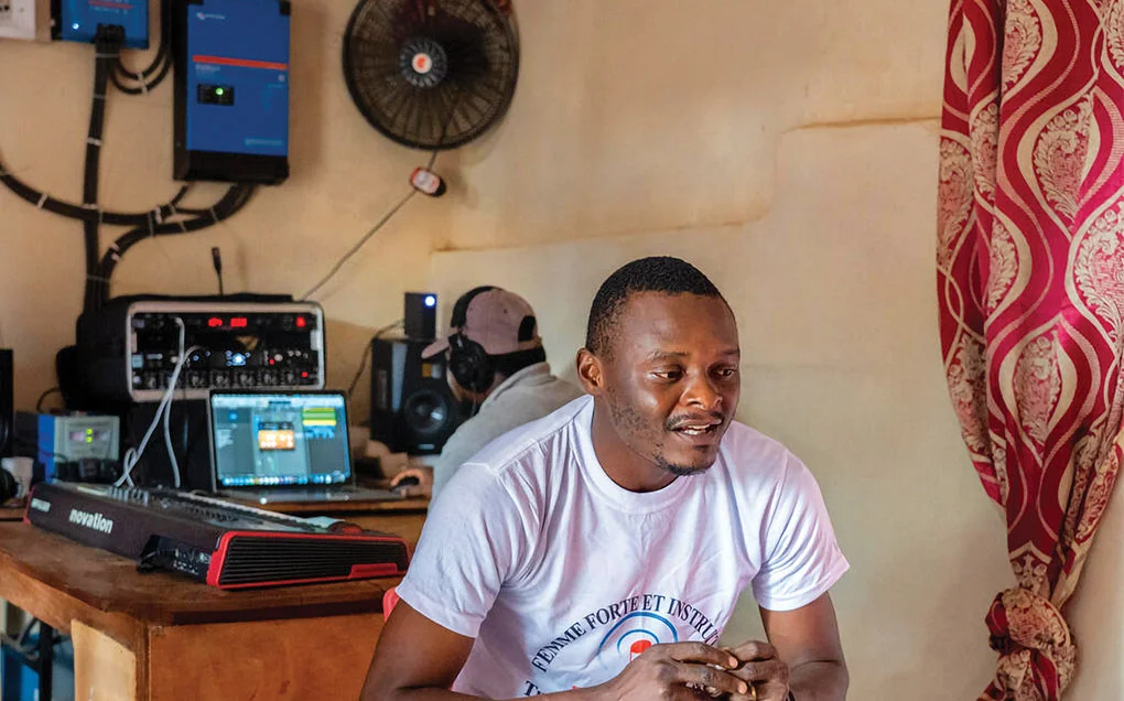 A man sits, wearing a white shirt and looks down. 